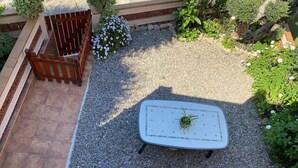 Ein Gartenbereich mit Tisch, Kies und Pflanzen.