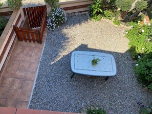 Ein Gartenbereich mit Tisch, Kies und Pflanzen.
