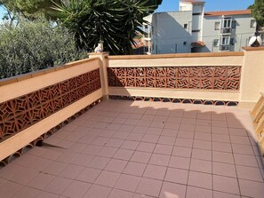 A rooftop terrace with patterned railings, a tiled floor, and a view of buildings in the background. - Holiday Home 'Casa Paqui Con Piscina Y Tenis' with Shared Pool, Shared Garden and Wi-Fi (L'Escala)