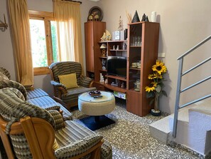 Ein Wohnzimmer mit einer Sofagarnitur, einem Fernseher, einem Bücherregal und einer Treppe.
