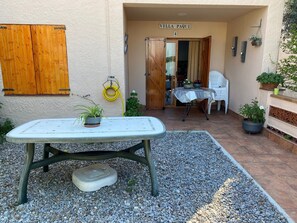 En patio med et bord, stole, plantekasser og et skilt med teksten 'Villa Paqui'.