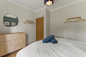 Ein Schlafzimmer mit einem Bett, einem Holzschrank, einem Spiegel und einer Tür.