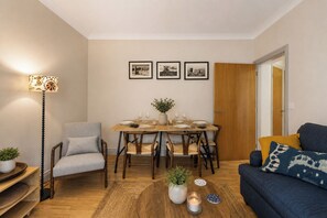 A cozy living room with a dining area, a sofa, a lamp, and a door leading to another room. - Comfortable 1 BDR Flat in Winchester (Winchester)