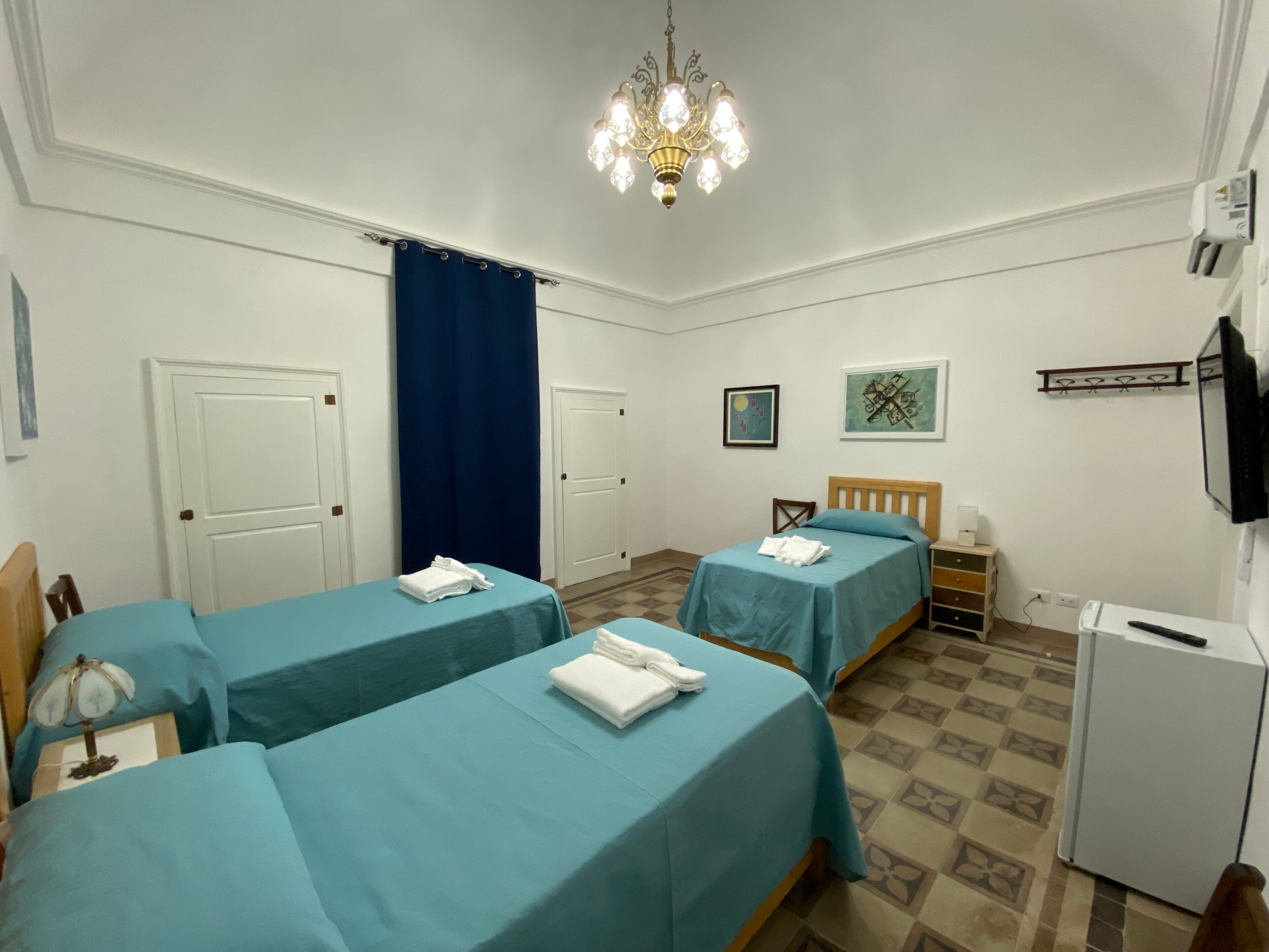 A hotel room with two beds, a desk, a chair, a television, and a refrigerator.