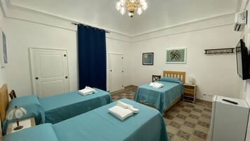 A hotel room with two beds, a desk, a chair, a television, and a refrigerator.