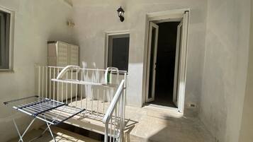 Una stanza con una rastrelliera metallica, un armadietto bianco e una porta che dà su un'altra stanza.