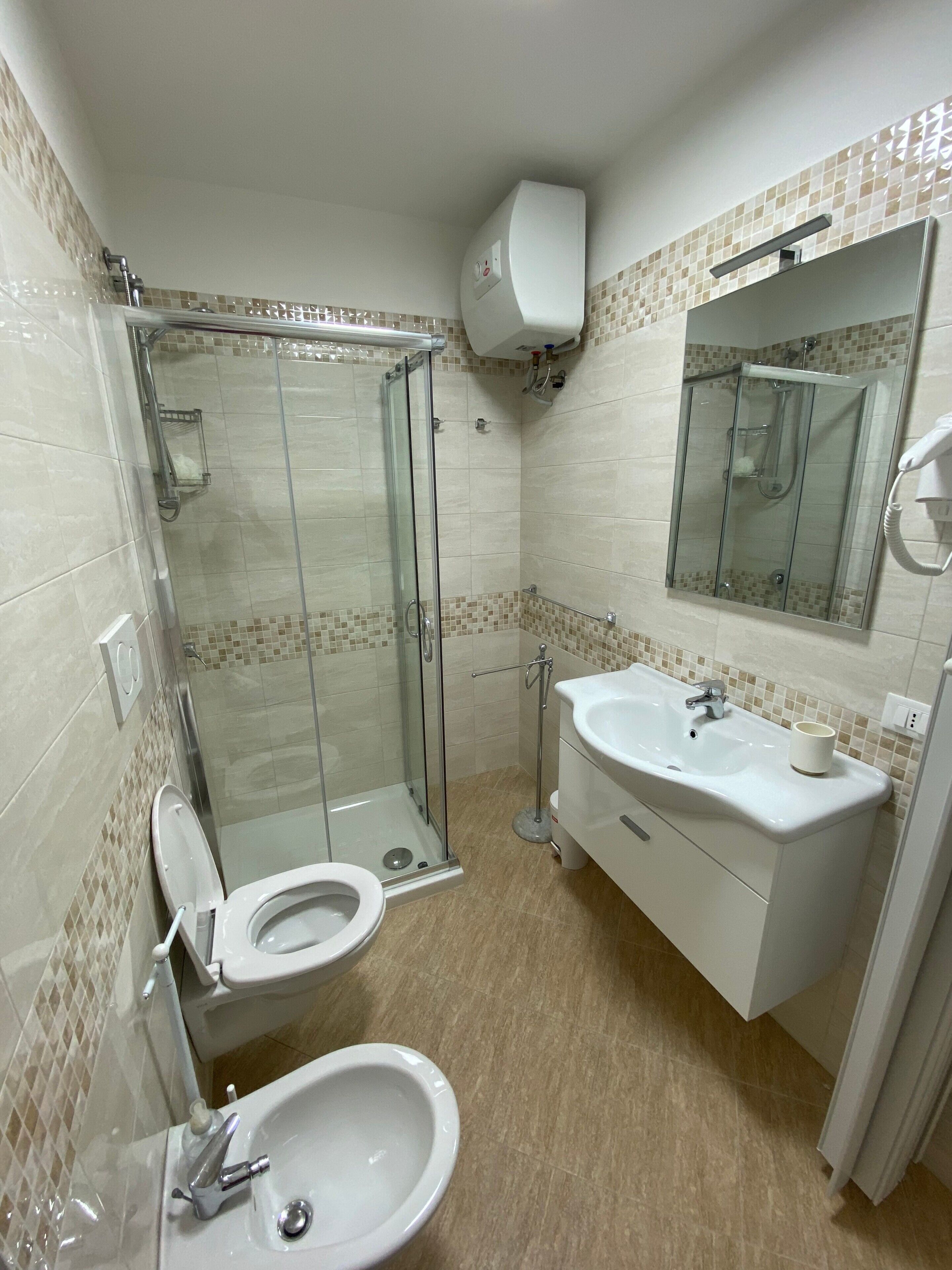 Une salle de bain avec une douche à parois de verre, des toilettes, un lavabo et un miroir.