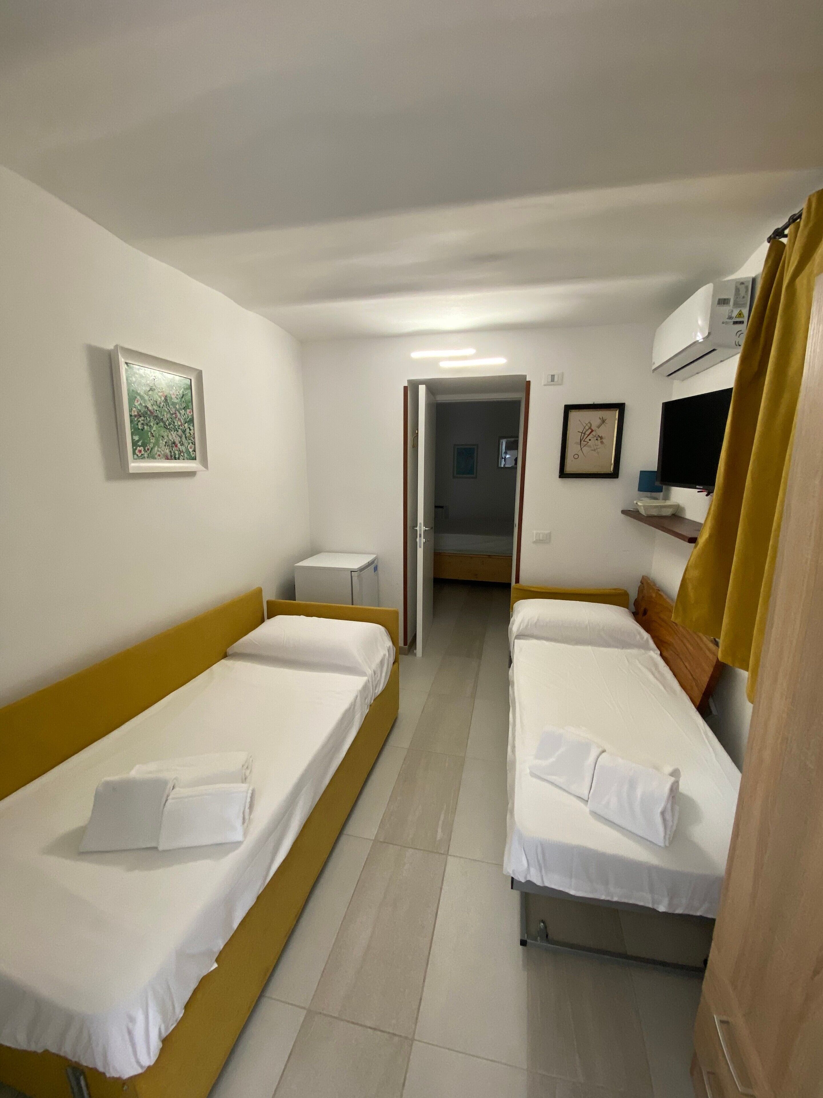 A room with two beds, a small table, a TV, and a door leading to another room.