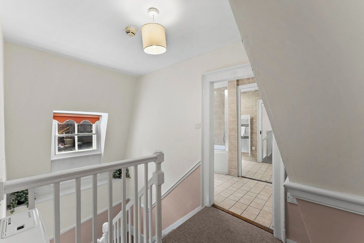 A staircase with a white railing, beige walls, and a light fixture.