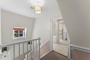 A staircase with a white railing, beige walls, and a light fixture. - Stylish Central Winchester Abode (Winchester)