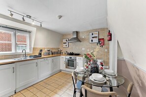 A modern kitchen with white cabinets, a gas stove, and a dining area with a glass table and chairs.