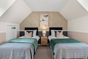 Une chambre avec deux lits, une table de chevet avec une lampe et une œuvre d’art accrochée au mur.