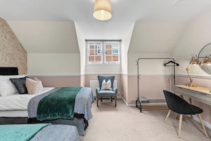 A bedroom with a bed, two chairs, a desk, a lamp, and a window. - Stylish Central Winchester Abode (Winchester)