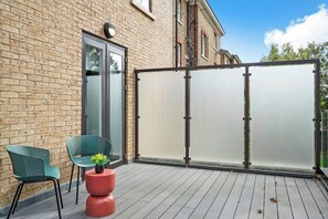 A balcony with a wooden floor, a glass door, and a metal partition. - Comfortable London Retreat - Sleeps 6 (London)