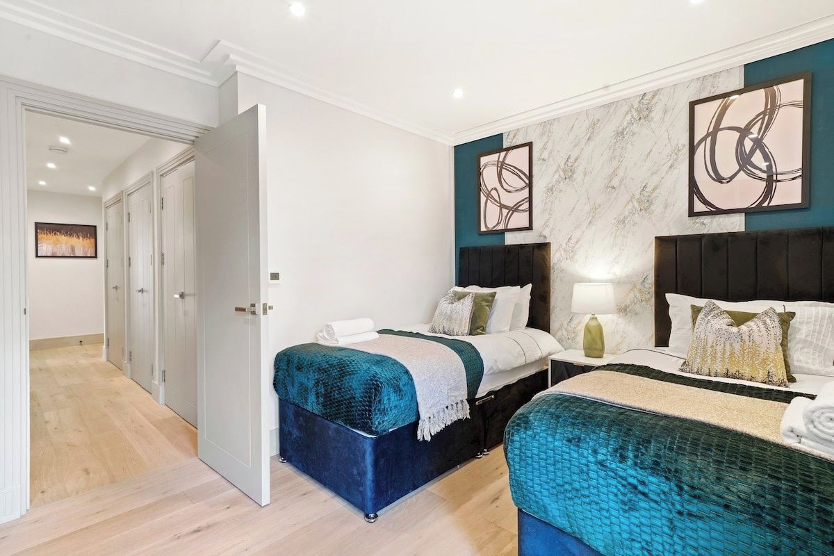 A hotel room with two beds, a marble wall, abstract art, and a wooden floor.