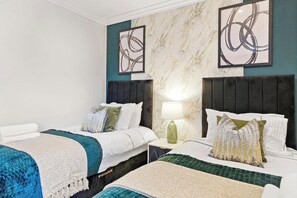 Habitación de hotel con dos camas, pared de mármol, arte abstracto y una mesita de noche con lámpara.