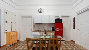 A compact kitchen with white cabinetry, a red refrigerator, a glass dining table, and a patterned floor. - Apartment 'Touristhouse Monopoli 10' with Balcony, Wi-Fi and Air Conditioning (Monopoli)