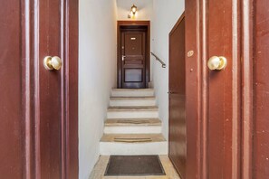 A wooden staircase leading to a dark wooden door with a light fixture above it. - Apartment 'Touristhouse Monopoli 10' with Balcony, Wi-Fi and Air Conditioning (Monopoli)