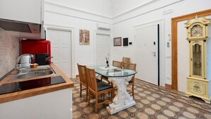 A compact kitchen with a red appliance, a dining table with chairs, and a decorative clock. - Apartment 'Touristhouse Monopoli 10' with Balcony, Wi-Fi and Air Conditioning (Monopoli)