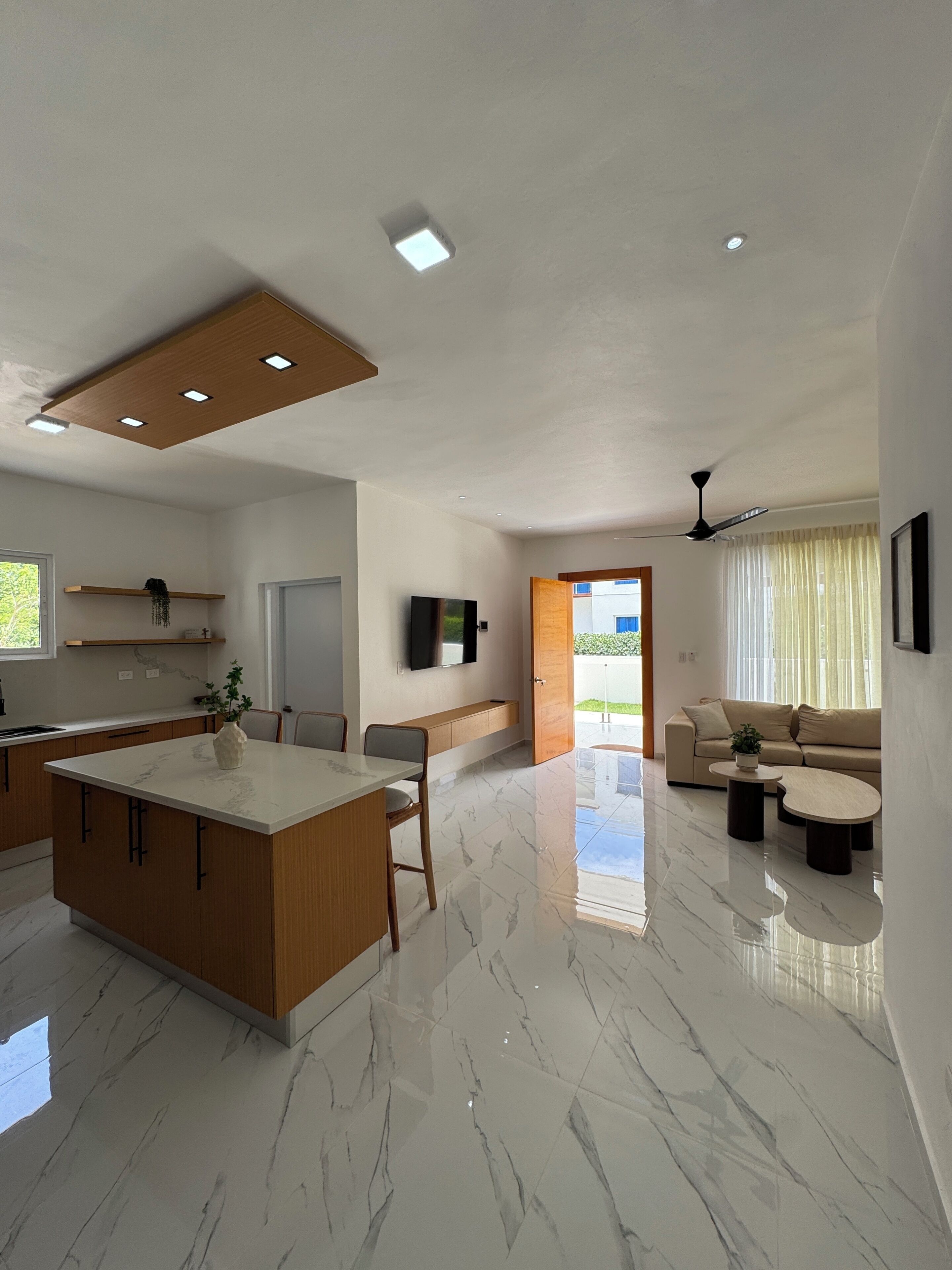 A modern kitchen with a marble countertop, wooden cabinets, and recessed lighting.