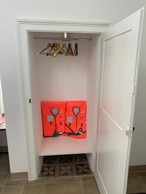 Ein Schrank mit einer Kleiderstange und zwei orangefarbenen Rettungswesten.