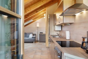 Una cocina moderna con armarios de madera, horno empotrado y pileta de acero inoxidable.