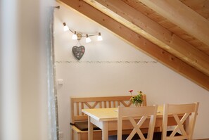 Una mesa de comedor de madera con sillas, una decoración con forma de corazón y una guirnalda de luces en la pared.