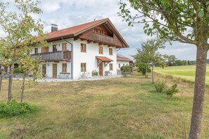 Ein zweistöckiges Haus mit rotem Ziegeldach, Holzbalkon und einem Rasen.