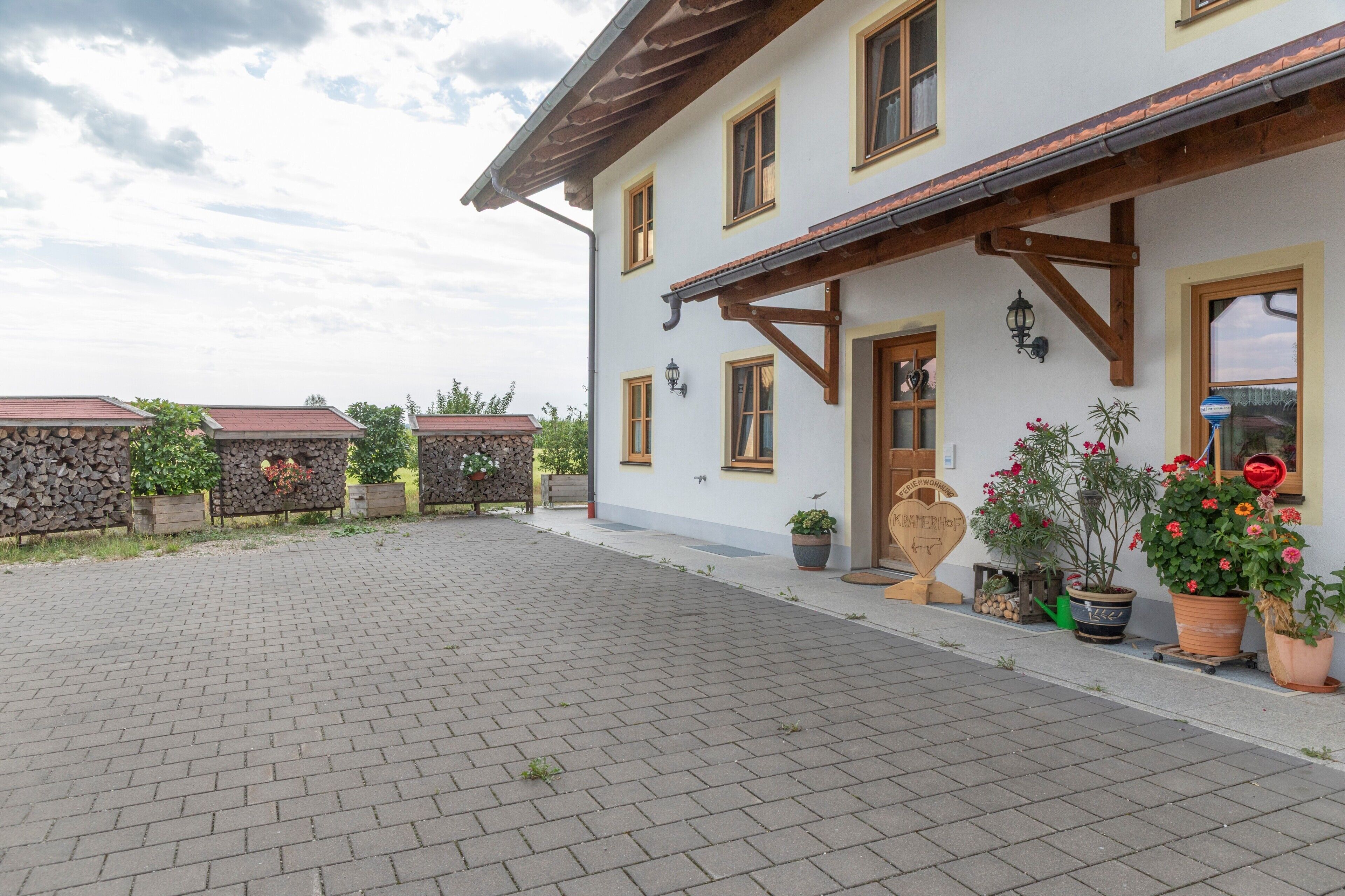 A building with a paved courtyard, wooden beams, and potted plants.