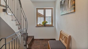 Un escalier avec des rampes en métal menant à un palier doté d’une fenêtre et d’un banc en bois.