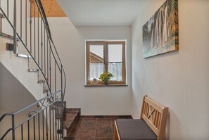 Eine Treppe mit Metallgeländern führt zu einer Zwischenebene mit einem Fenster und einer hölzernen Bank.