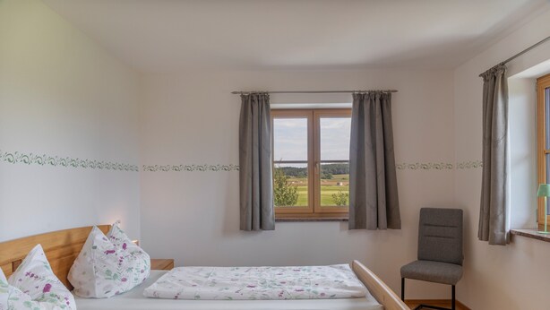 Une chambre avec deux lits, une chaise et une fenêtre avec des rideaux.
