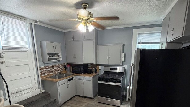 A compact kitchen with a dining area, a ceiling fan, and a refrigerator.