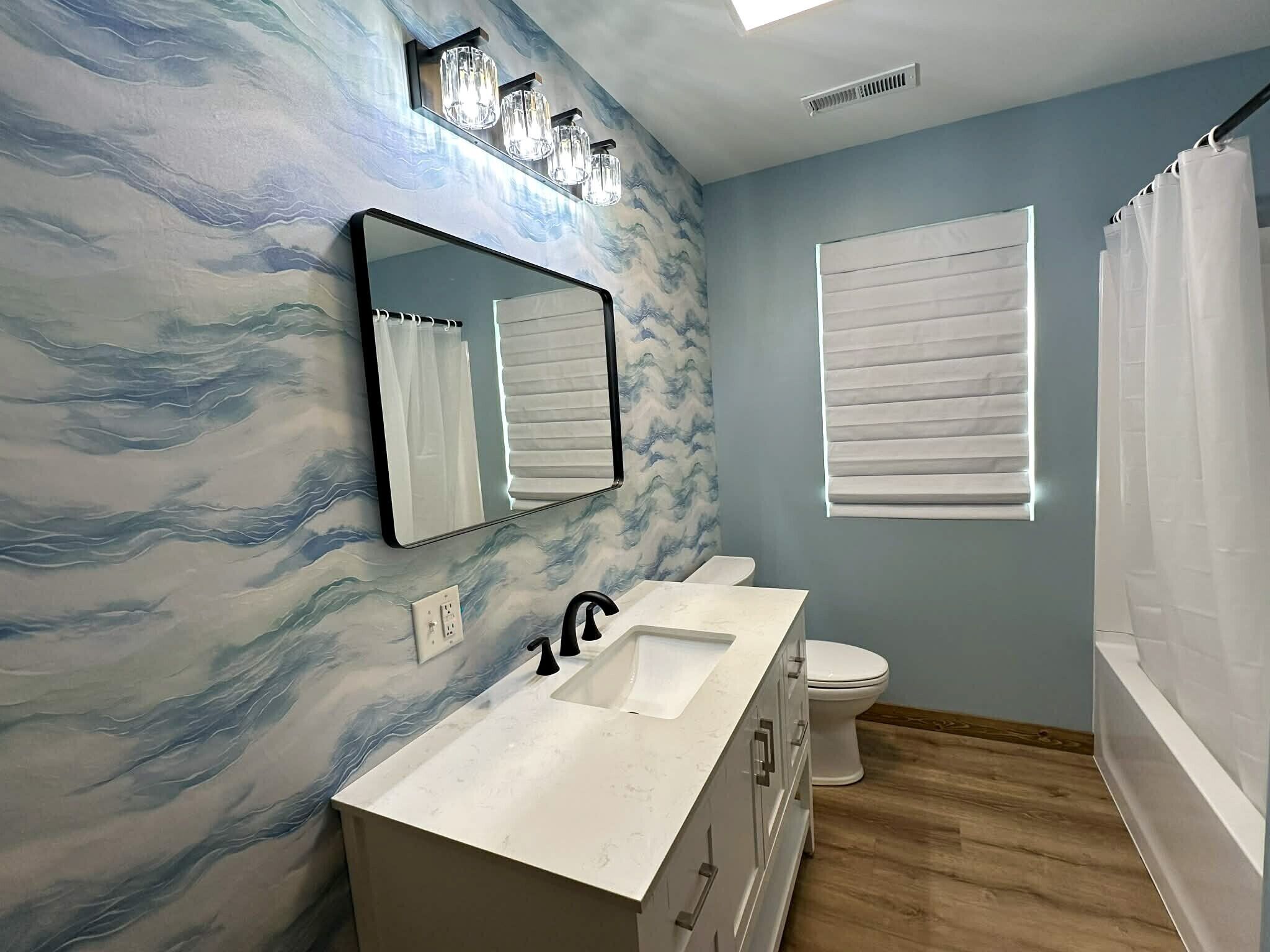 Ein Badezimmer mit Marmorwand, einem Waschbecken, einer Toilette und einer Duschvorhang.