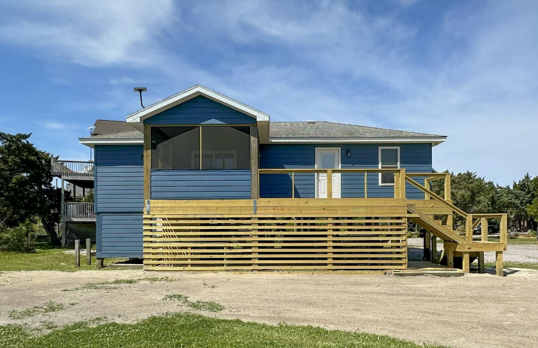 Un edificio de dos pisos con una terraza de madera y una escalera que sube al nivel superior.