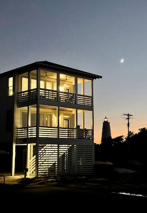 A two-story building with balconies and a lighthouse in the background.