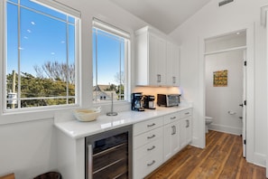 A modern kitchen with white cabinetry, a built-in oven, and a coffee maker.