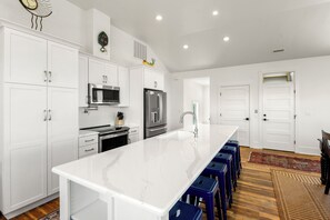 A modern kitchen with white cabinetry, stainless steel appliances, and a marble countertop.