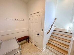 Un couloir avec un banc en bois, un porte-manteau et un escalier avec des marches en bois.