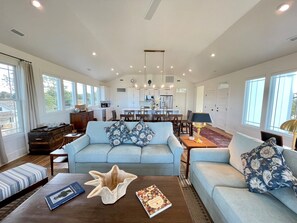 A spacious living room with a light blue sofa, a coffee table, and a dining area in the background.