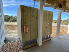 A wooden fence with a hanging object, a concrete floor, and a clear sky.