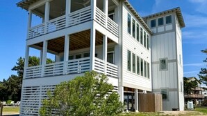 A two-story building with a balcony on the upper level and a separate section on the lower level. - Wyf of Bathe: Silver Lake Views with docking available. (Ocracoke)