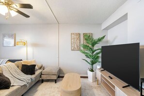 Een moderne woonkamer met een bank, salontafel, televisie en decoratieve wandkunst.