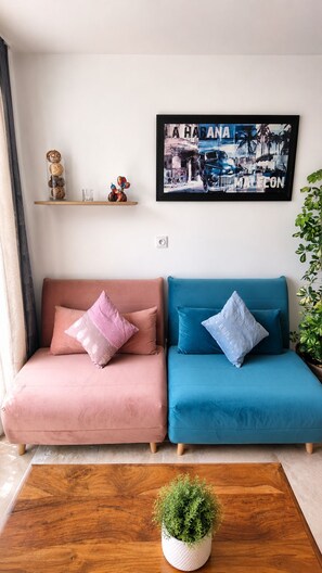 Ein Wohnzimmer mit einer Sofagarnitur, einem Couchtisch, einem gerahmten Bild und einer Topfpflanze.