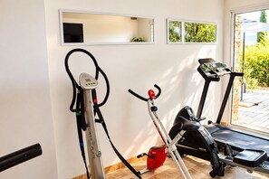 Kotikuntosali, jossa on kuntopyörä, juoksumatto ja crosstrainer.