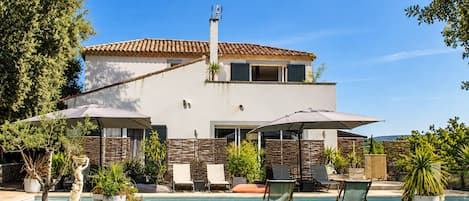 A modern two-story house with a swimming pool, outdoor seating, and a well-maintained garden.