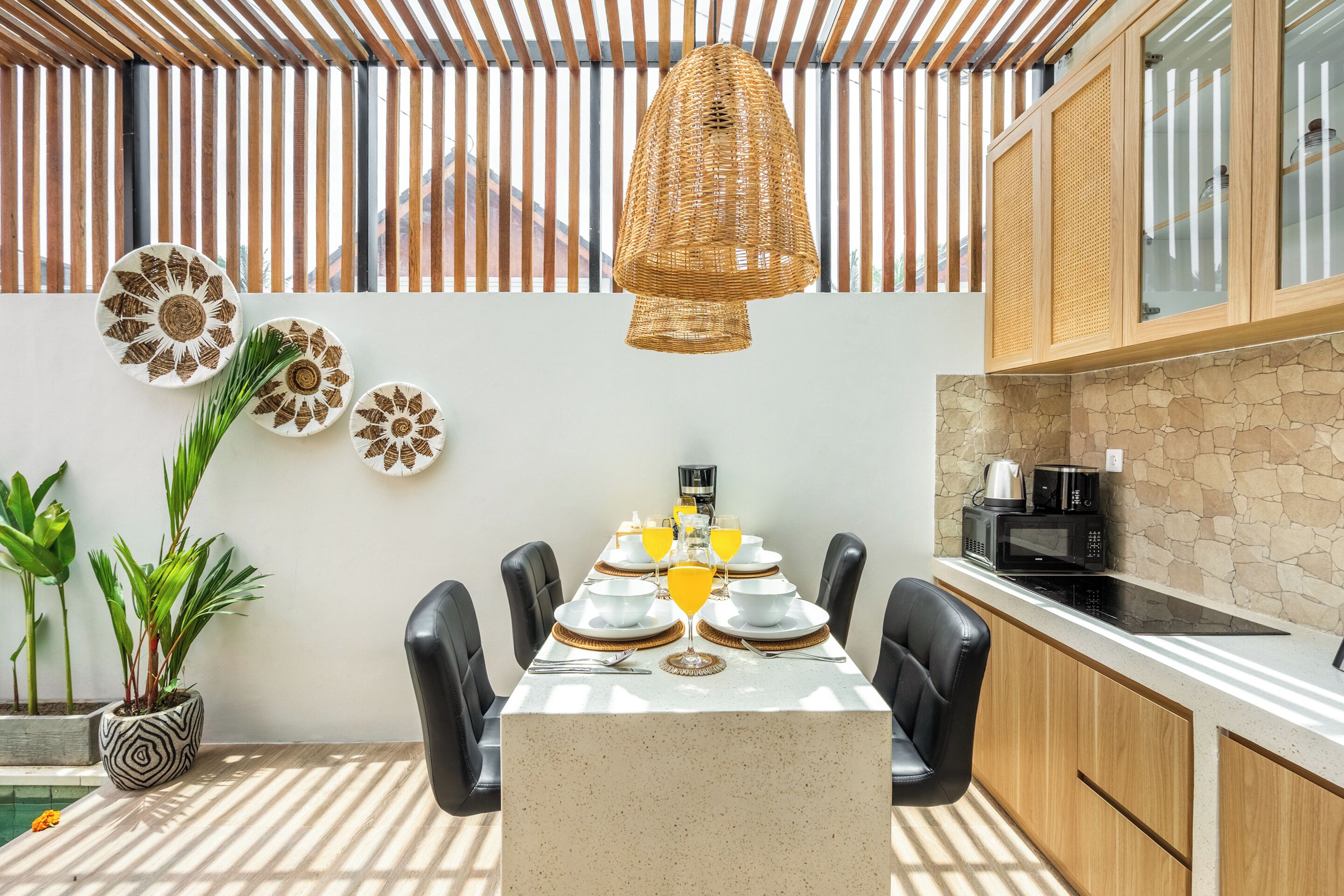 Comedor con una mesa dispuesta para cuatro personas, rodeada de sillas, y una lámpara colgante arriba.