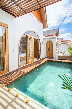 Ein Poolbereich mit Holzterrasse, Steinmauer und Holztür.