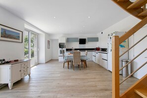 Een ruime keuken met een eethoek, houten vloeren en een trap.