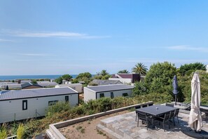 A coastal residential area with mobile homes, a patio with outdoor furniture, and a view of the sea. - Villa 'Ty Killy' with Panoramic Sea View, 1-Min Walk to Beach, Concierge Service (Sarzeau)